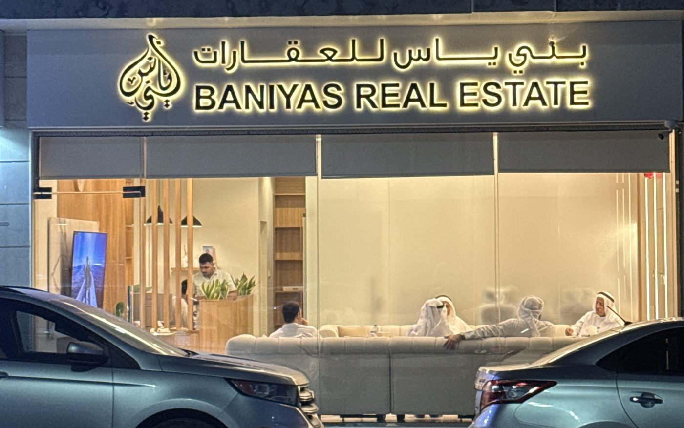 Baniyas Real Estate office front at night with the sign lit