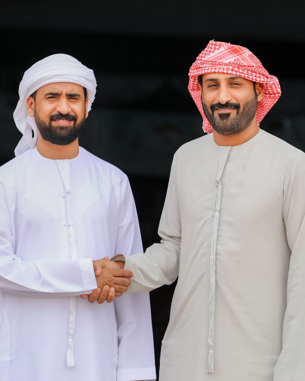 Two men in traditional Emirati dress shaking hands
